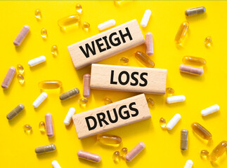 Medicine symbol. Concept words Weight Loss Drugs on wooden blocks. Beautiful yellow background with...
