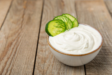 Cucumber sour cream tzatziki sauce on a wooden table.Tartar sauce. Traditional delicious appetizer. yogurt sauce. Tzatziki with ingredients cucumber, garlic,dill,lemon,mint. salad dressing.Copy space