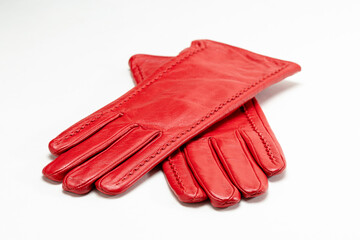 Folded red women's leather gloves, isolated on a white background. Smooth seams and soft texture indicate high quality manufacturing of the women's accessory.