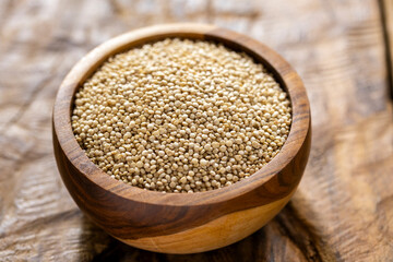 A pile of quinua grains is seen in the image, in a wooden container