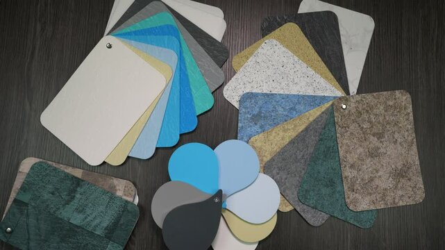 Many pool cladding samples on the table. Top view, hands pointing at different color combinations.