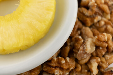 a vibrant pineapple ring nestled in a white bowl, surrounded by scattered walnuts, evoking a sense of natural sweetness and healthy snacking. Ideal for food blogs, healthy lifestyle content