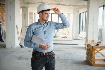 Architect holding blueprints and wearing a helmet