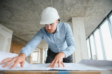 Architect holding blueprints and wearing a helmet