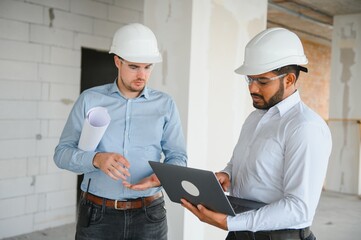 Two multiracial engineer working at site of a large building project. Team of engineer discus at...