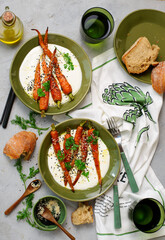 Baked baby carrots in honey glaze on whipped feta in a ceramic bowl . selective focus. hugge style