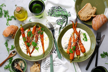 Baked baby carrots in honey glaze on whipped feta in a ceramic bowl . selective focus. hugge style