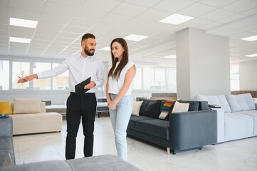 A young salesman consults a female customer in a furniture store