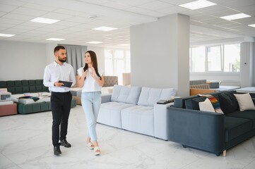 Salesman meeting young woman in furniture salon