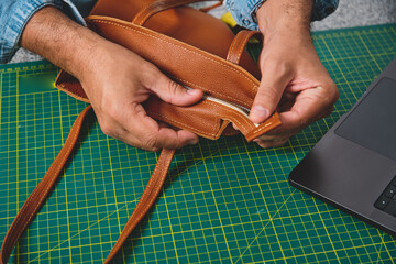 Artisan checking the zipper of a handmade leather bag in a small business workshop © rjankovsky