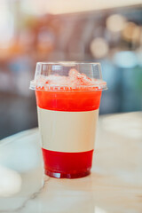 Refreshing Fruit Beverage with Ice in Transparent Cup on Marble Surface in Bright Cafe Environment