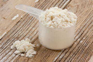 scoop of whey protein isolate powder on a grunge wooden table background