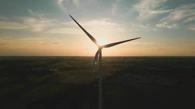 Aerial drone shot of a wind turbine at sunset, symbolizing clean and renewable energy in harmony with nature