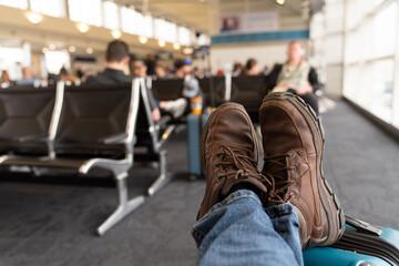 Traveler Relaxing At Airport With Feet On Suitcase