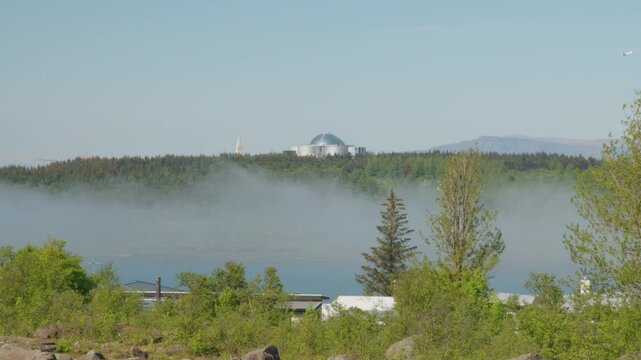 Small plane landing in Reykjavik over valley fog on summer day