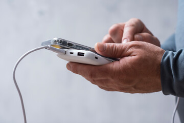 Close-up of a man holding a power bank and charging a smartphone. Portable charger for phone and...