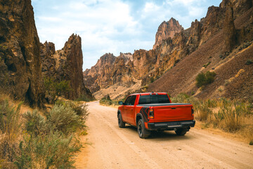 Red truck is off-roading through Succor Creek State Natural Area in Owyhee Canyon near Leslie Gulch in Oregon, USA