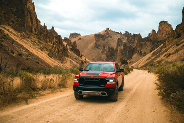 Red truck is off-roading through Succor Creek State Natural Area in Owyhee Canyon near Leslie Gulch in Oregon, USA