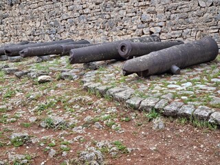 Old Rusted Cannons Resting by Ancient Stone Fortress Wall