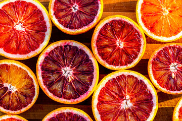 Red blood halved oranges close up on a wood background. Top view. Flat lay of fresh orange citrus...