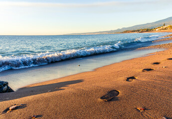footstep track on sea shore sand with vawes and surf on background