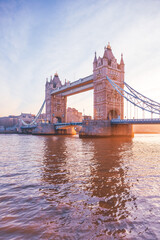 Fototapeta na wymiar Tower Bridge stands majestically as the sun rises, casting warm hues over the Thames River. This iconic landmark is illuminated, showcasing its architectural beauty at dawn.