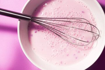 Protein cocktail pink colored with berry pieces. The process of making a cocktail with a steel whisk