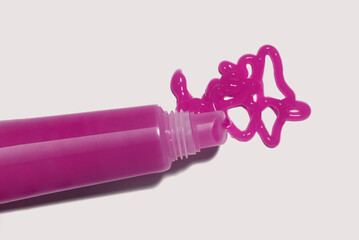 Lip gloss or tint or lip balm pink colored smudge and plastic tube sample on isolated gray...