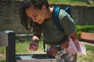 Woman Drinking From a Fountain in a Sunlit Outdoor Setting