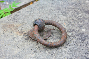 Heavy iron ring embedded in weathered concrete surface shows signs of age and corrosion