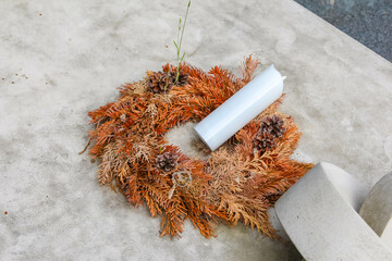 Traditional dried flower wreath with white ribbon placed on concrete memorial stone