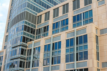 A close-up view of the intricate, textured facade of a modern skyscraper, highlighting its geometric patterns and reflections.