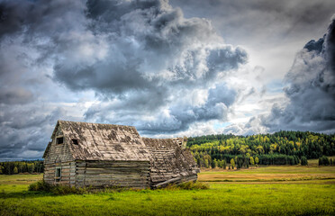 old abandoned house in green field with dark contrasty clouds