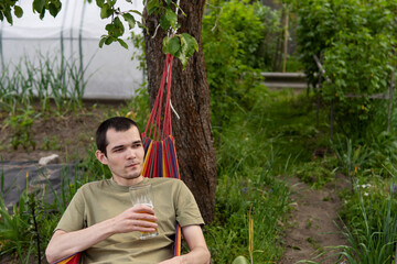 A man with a beer glass lies in a hammock