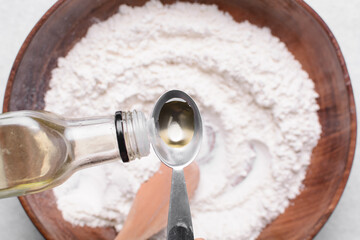 olive oil into a measuring spoon, measuring a tablespoon of oil