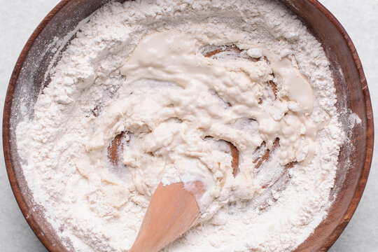 Overhead view of paratha dough being mixed in a wooden bowl, top view of flaky flatbread dough in a wood bowl, process of making paratha