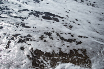 Foamy sea wave washing over a pebbly shore
