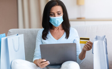 Quarantine, Online Shopping And Self-Isolation. Mature woman wearing medical face mask, holding...