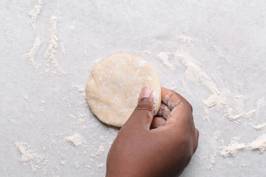 Overhead view of paratha dough being rolled out, top view of flaky flatbread dough, process of making paratha	