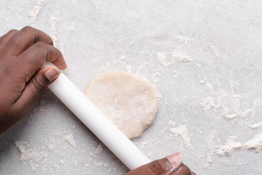 Overhead view of paratha dough being rolled out, top view of flaky flatbread dough, process of making paratha	
