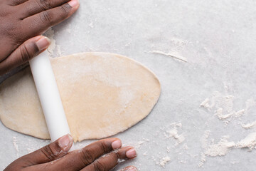 Overhead view of paratha dough being rolled out, top view of flaky flatbread dough, process of making paratha	