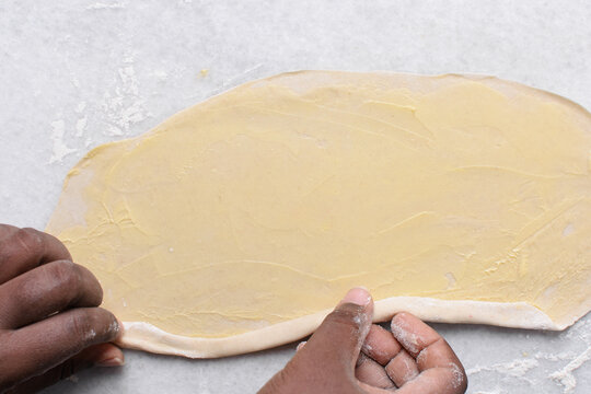 Overhead view of rolled paratha dough on a marble countertop, top view of flaky flatbread dough, process of making paratha