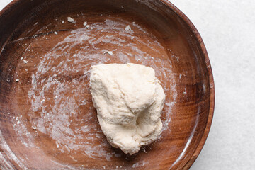 Overhead view of paratha dough being mixed in a wooden bowl, top view of flaky flatbread dough in a wood bowl, process of making paratha