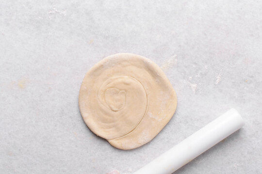 Overhead view of paratha dough being rolled out, top view of flaky flatbread dough, process of making paratha