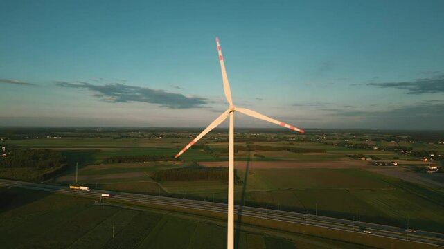 Aerial drone shot of a wind turbine at sunset, symbolizing clean and renewable energy in harmony with nature