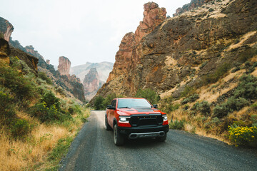 Red truck is off-roading through Succor Creek State Natural Area in Owyhee Canyon near Leslie Gulch in Oregon, USA