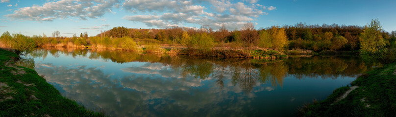 Fototapeta premium Panorama of forest lakes in spring, young leaves and freshly blossomed buds of trees and shrubs