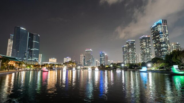 Timelapse video of Songdo Central Park in Incheon, South Korea, near Seoul, at night. Modern highrise towers and illuminated boats are reflected in the pond.