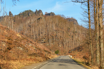 Autumn landscape with winding road through rocky forested hills