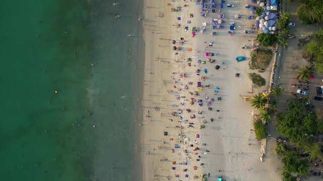 Strand in Thailand, man sieht viele Menschen und das t&uuml;rkis blaue Meer.